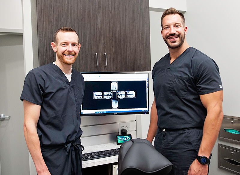 Addison and a fellow Capital Dental dentist smiling in front of an x-ray