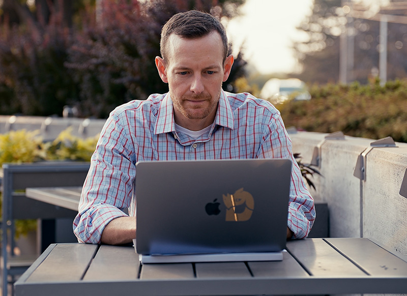 Addison sitting on a patio looking at his laptop