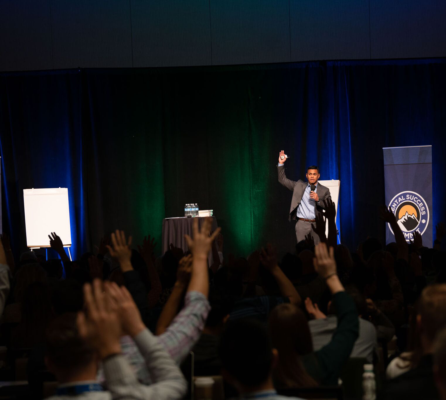 dental success summit photo of crowd raising their hands with the speaker on stage